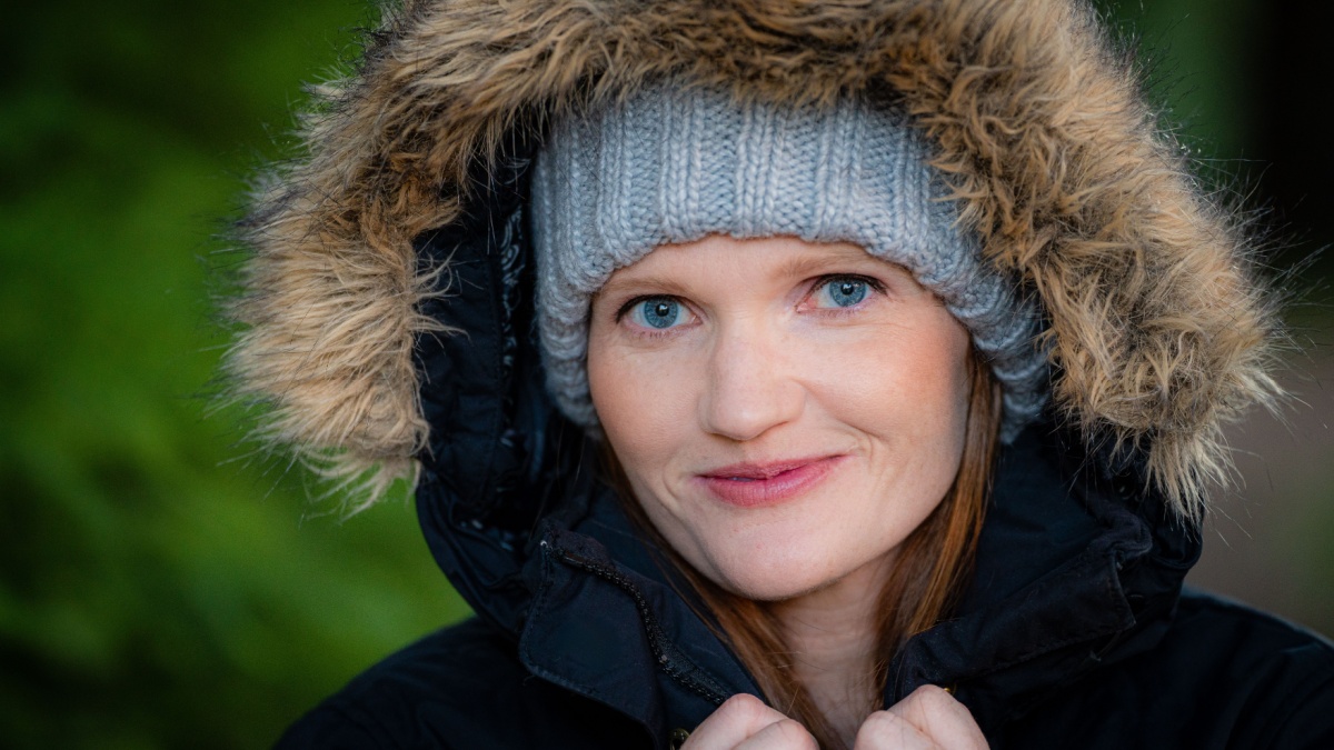Close up portrait of Caucasian white red head women with parka jacket in cold weather with smirk.