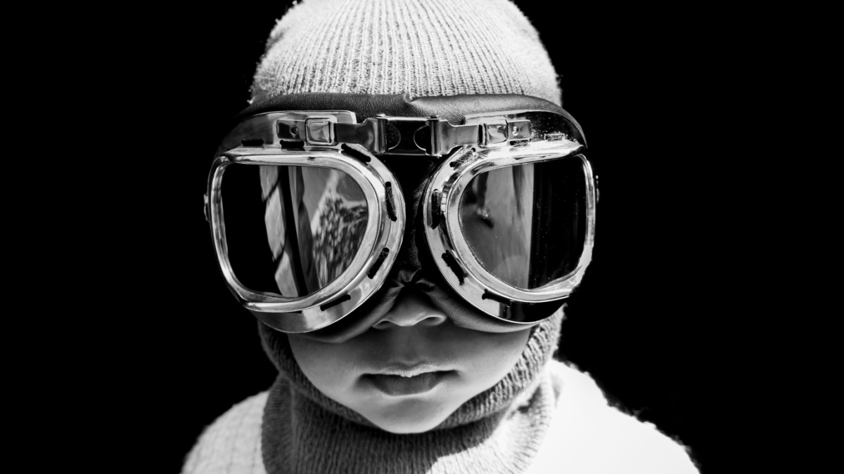 Portrait of an Asian boy pilot in vintage aviator helmet and goggles. Black and white vintage photograph.