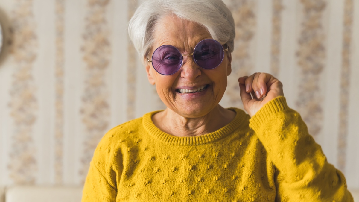 cheerful senior woman with purple sunglasses laughind widely seniority concept medium closeup indoors. High quality photo.