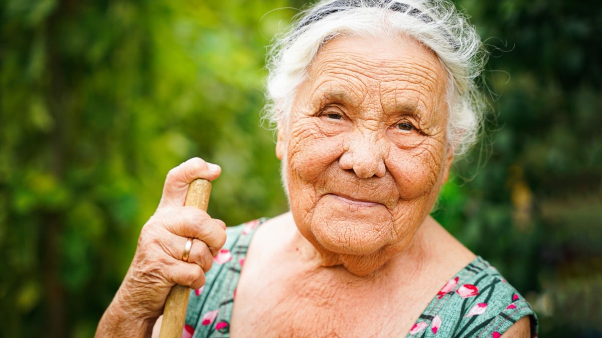 close up portrait of a senior woman in a garden. Very old lady of eighty years old outdoor in summer.