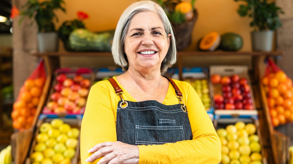 Female greengrocer working at the market shop - Food retail concept.