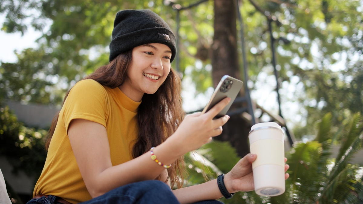 Gen Z eco go green woman asia sit happy relax at tree public park city life enjoy typing mobile phone drink coffee bottle use reuse tote bag care save the earth planet net zero waste clean future hope.