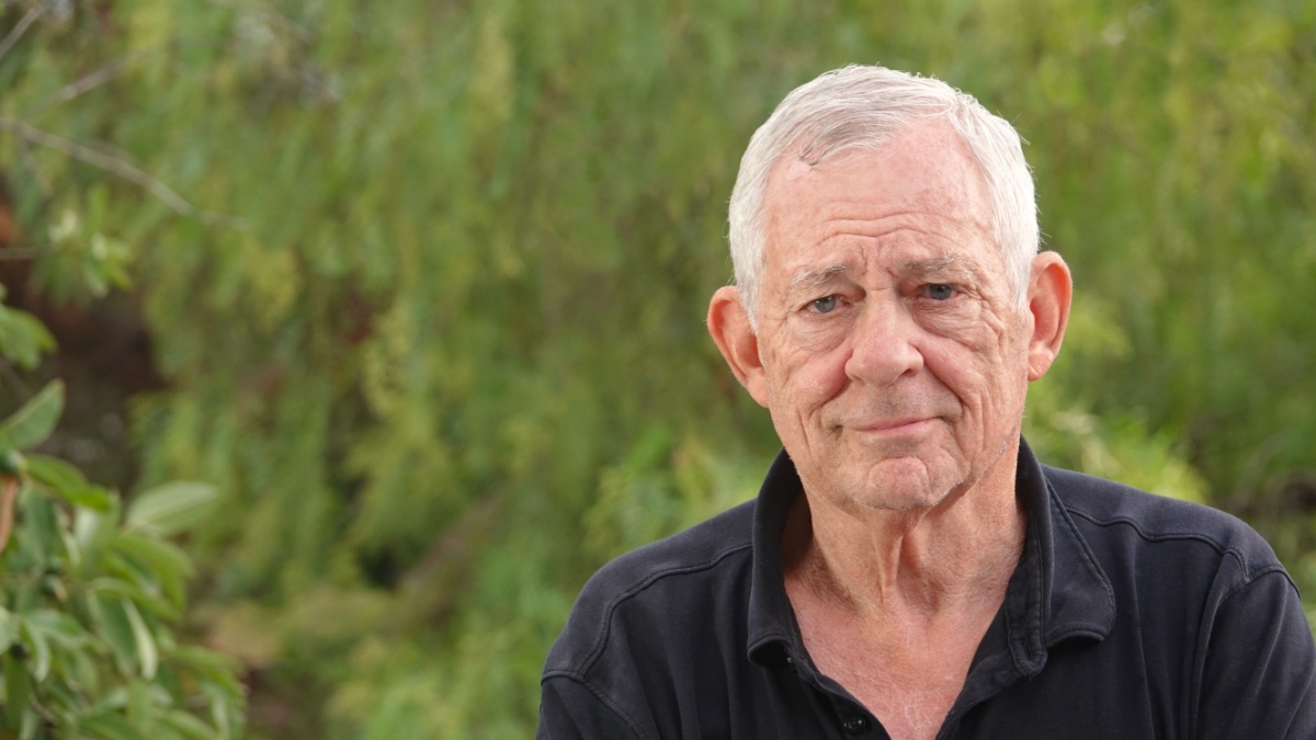 Outdoor portrait of a smiling, but still serious and thoughtful looking Octogenarian set in green nature background.