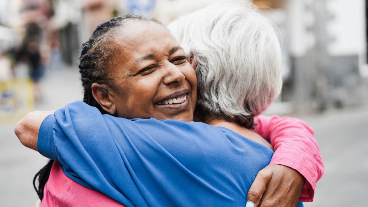 Senior multiracial women meeting and hugging each others outdoor.