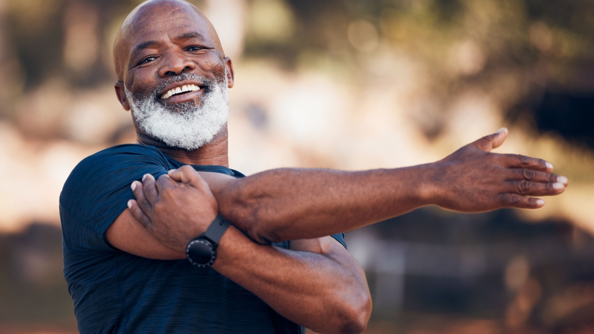 Black man, portrait and stretching for exercise outdoor in nature forest for fitness and healthy lifestyle. Senior person smile for workout, training and muscle warm up for cardio health and wellness.