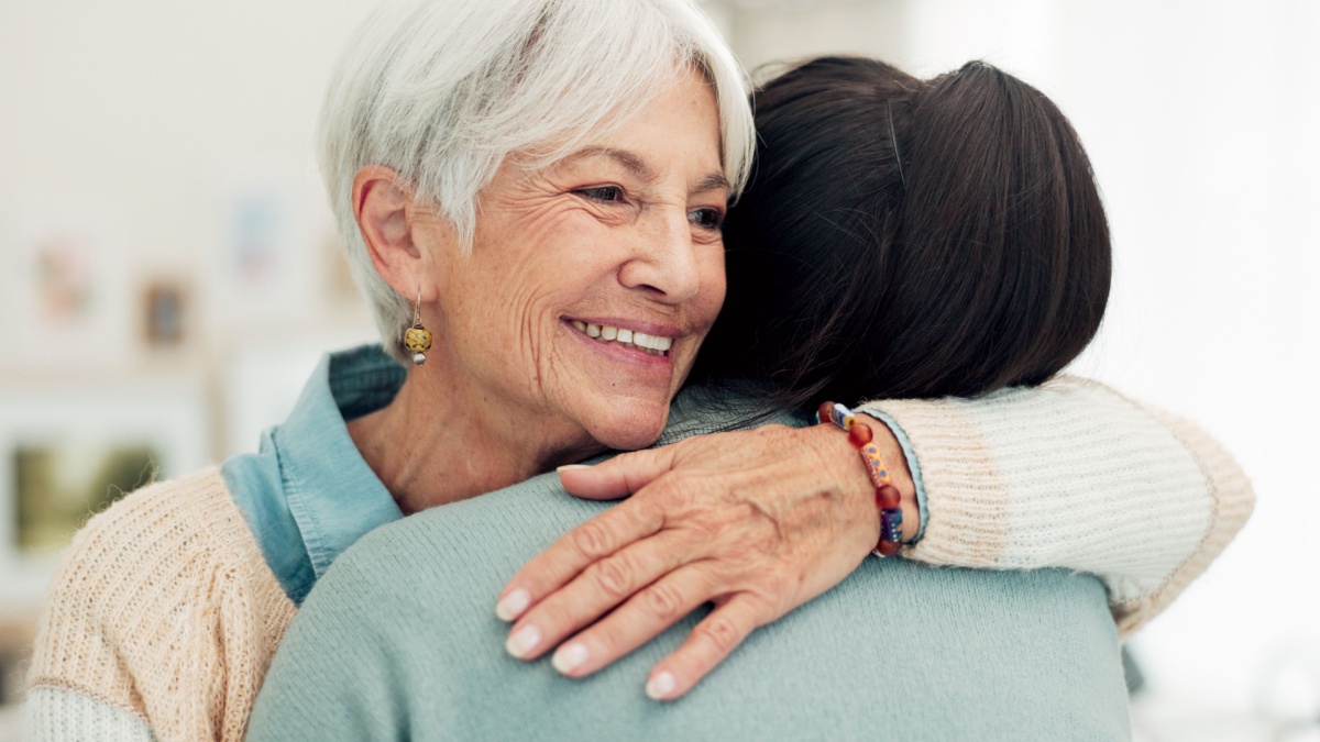 Happy senior woman, hug and elderly care for thank you, gratitude or support for caregiver at home. Mature female person or patient embracing medical or healthcare worker in trust, happiness or house.
