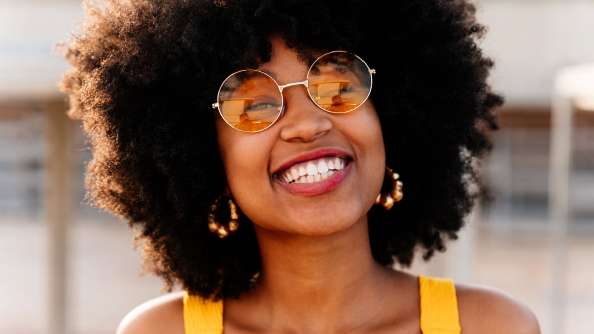 Beautiful young happy african woman with afro curly hairstyle strolling in the city - Cheerful black student portrait outdoors