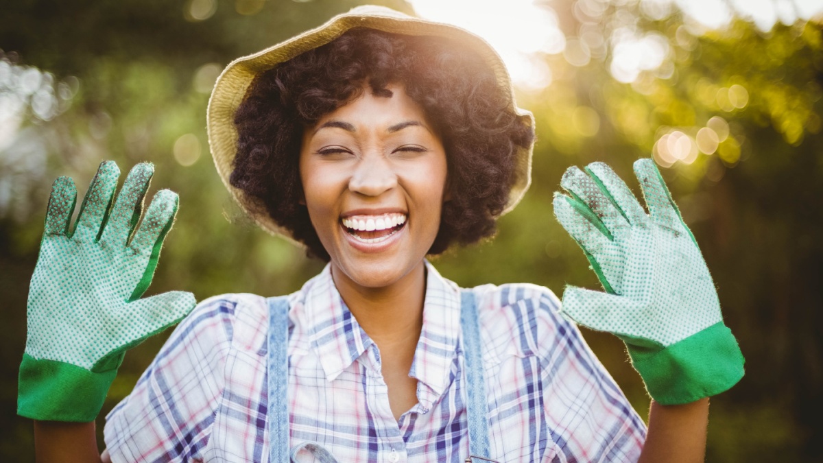 happy woman showing her gardening gloves in the garden.