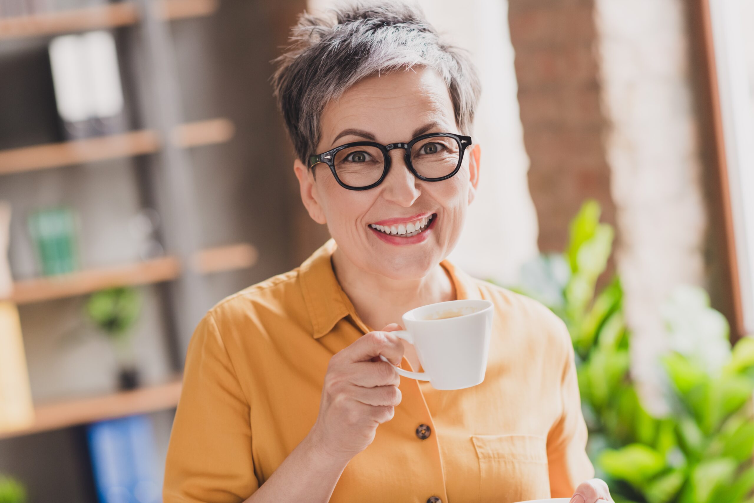 Photo of lovely mature lady drink coffee hold cup dressed yellow formalwear modern workplace success business owner home office.