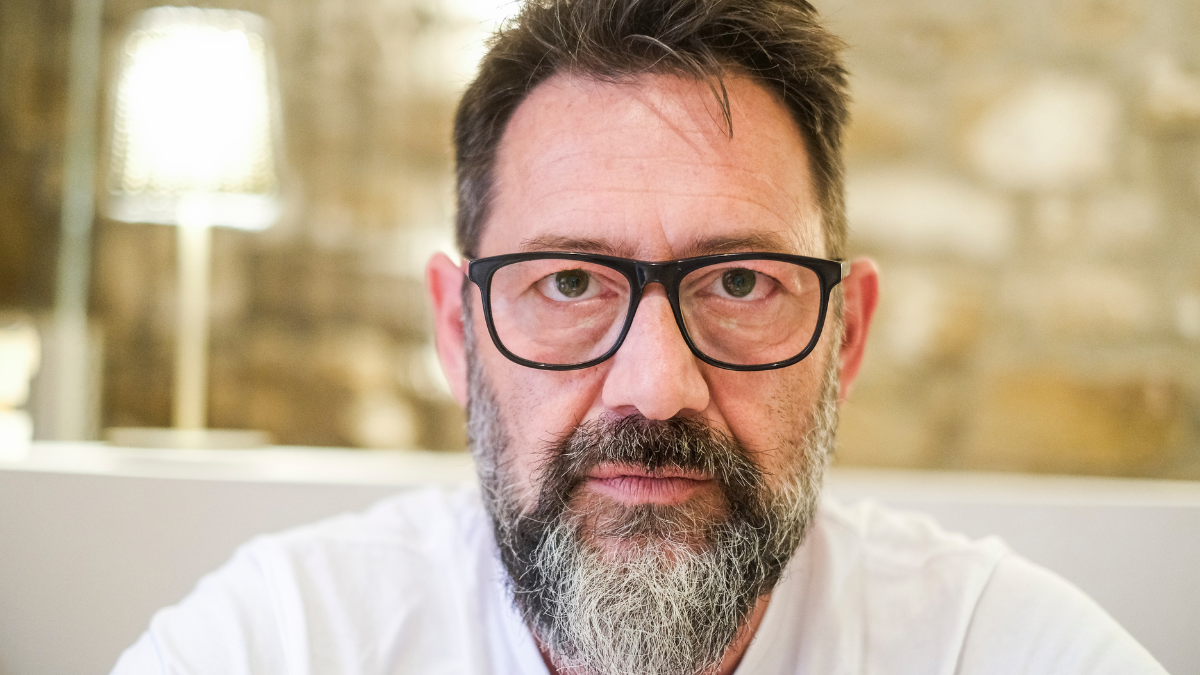 A serious-looking man, standing at home, appears deeply angry with a stern expression. His face shows intense frustration and stress, highlighting difficulties in his personal life and career.