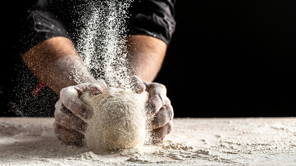 Photo of flour and men hands with flour splash. Cooking bread. Kneading the Dough. Isolated on dark background.