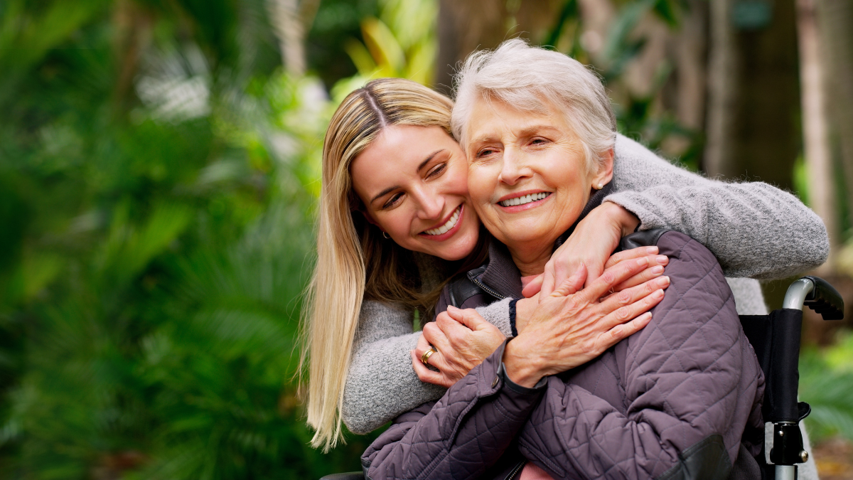 Wheelchair, senior and woman hug in park for retirement, rehabilitation and support. Person with disability, mother and daughter embrace in nature for healthcare, family care and mobility aid.