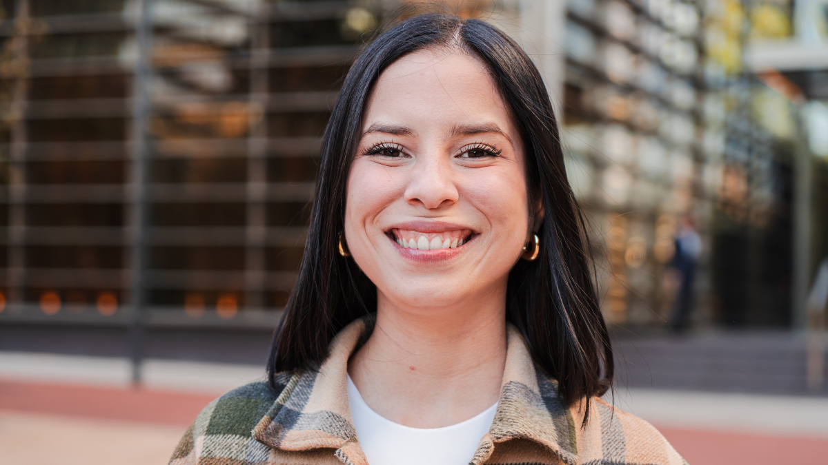 One hispanic woman looking at camera with friendly expression. Close up individual portrait of a latina female smiling, standing outside and staring front. Headshot of a pleased teenage latin girl.