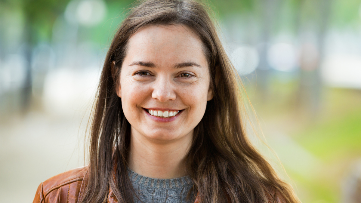 Portrait of young smiling brunette girl in fall day outdoors.