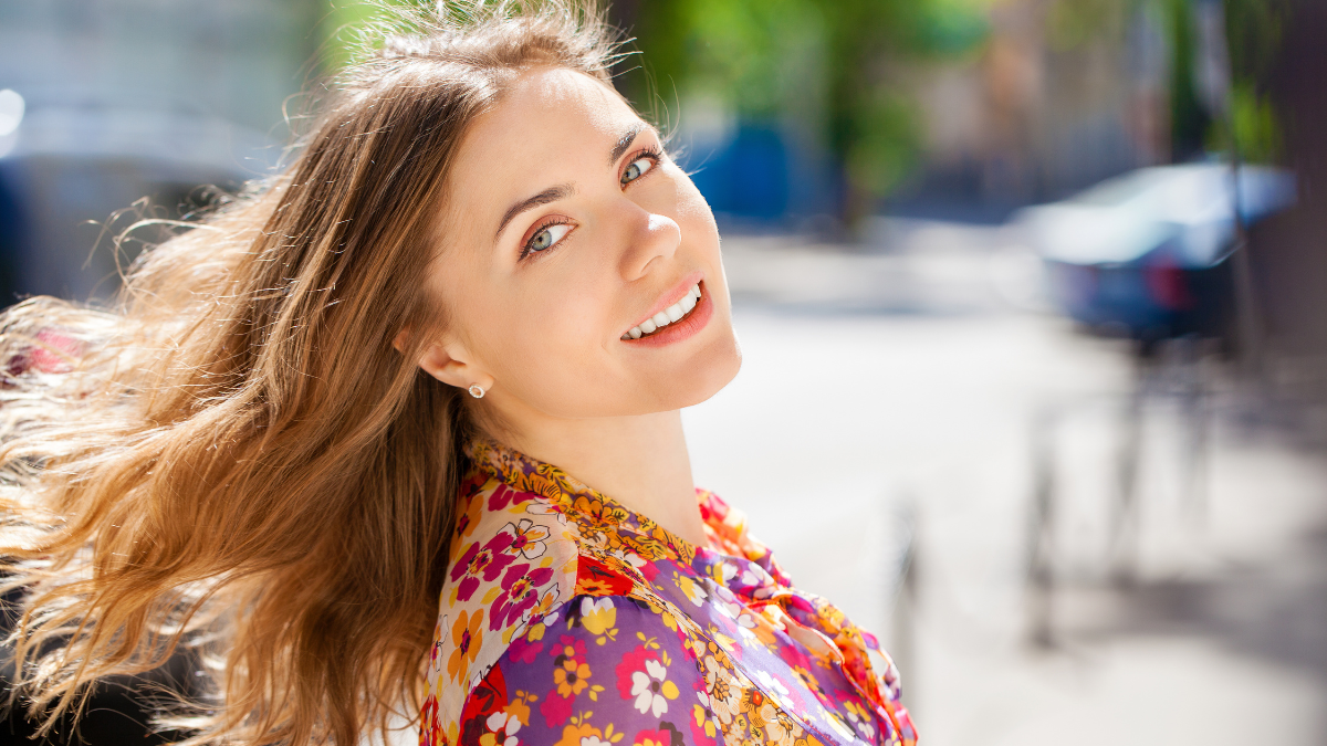 Portrait close up of young beautiful happy blonde woman in red dress, summer street outdoors.