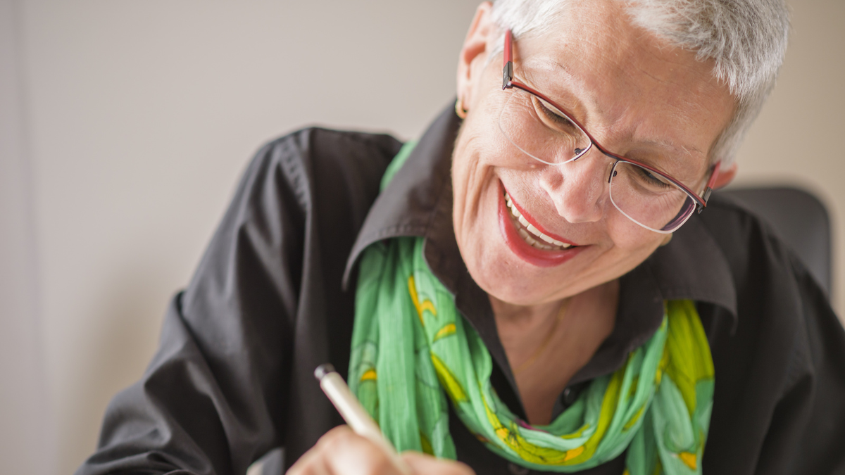 Senior old woman writing down letters on a piece of paper, recor.