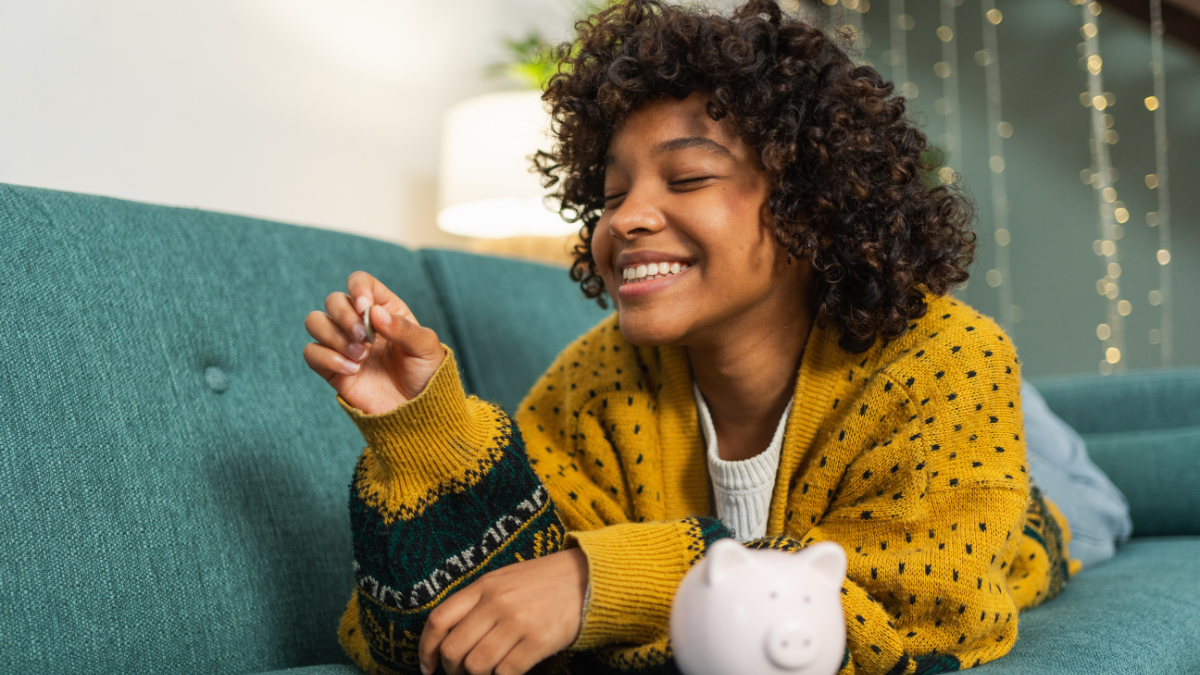 Saving money investment for future. African American girl putting money coin in pink piggy bank. Saving investment budget business wealth retirement financial money banking concept
