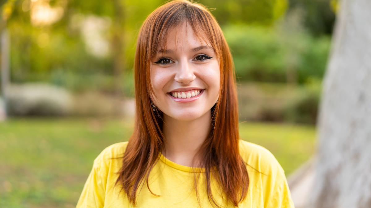 Young pretty redhead woman at outdoors With happy expression.