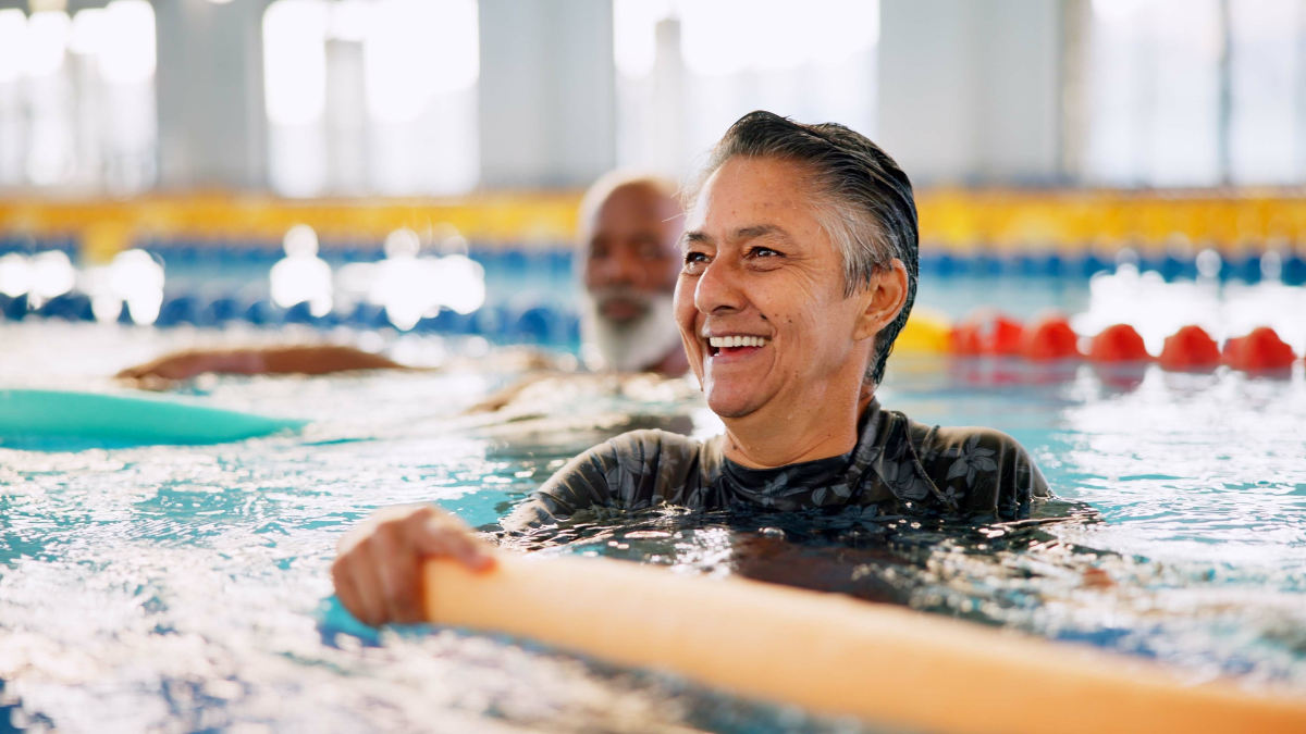 Swimming pool, senior people and woman with smile, exercise and water aerobics for fun. Pensioner, retirement and mature lady with fitness, wet and liquid with training, wellness and healthy with joy.