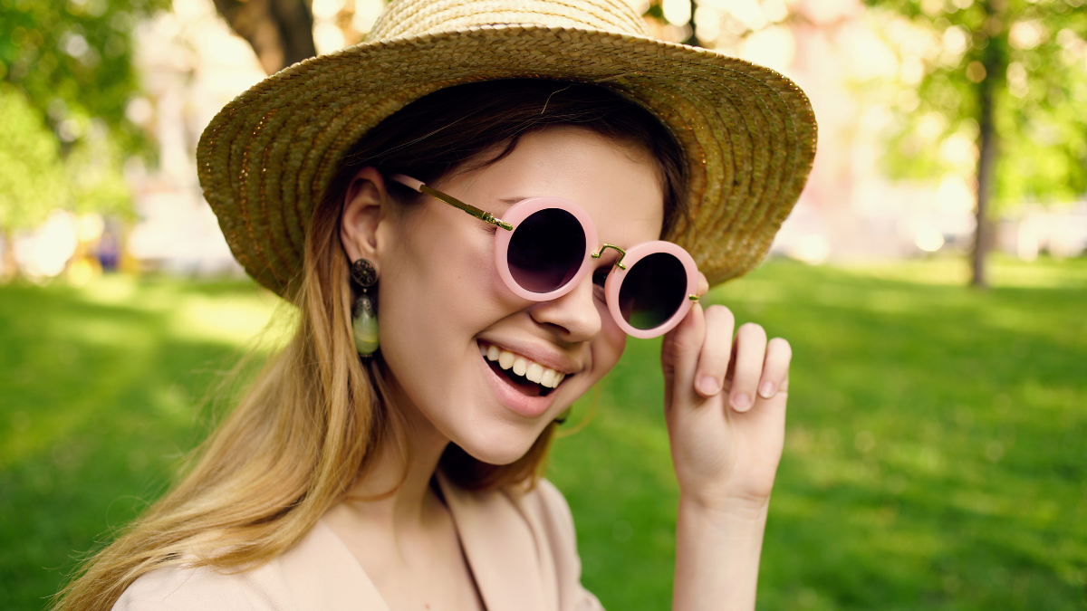 Woman with hat and glasses outdoors.