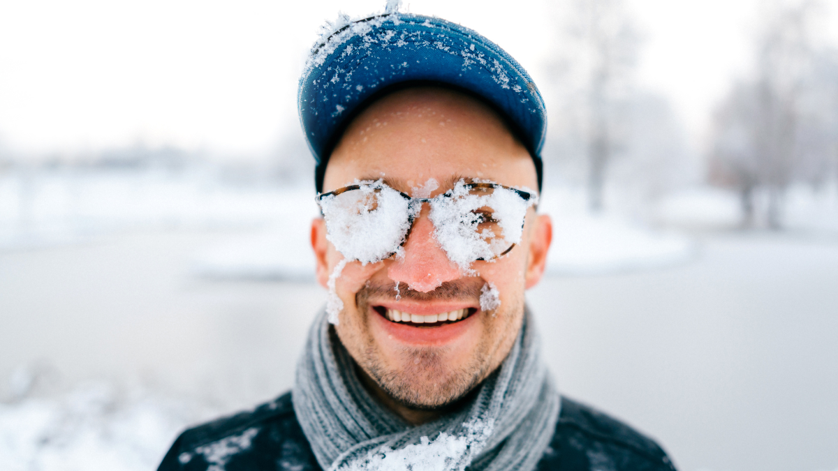 Closeup portrait of male face covered with snow. Crazy cheerful funny comic emotions.