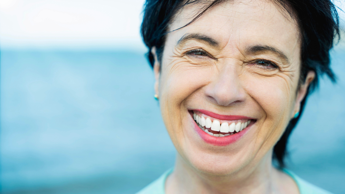 Close up portrait of senior woman smiling at camera outdoors - Happy aged female looking at camera - Healthy lifestyle and well being concept.