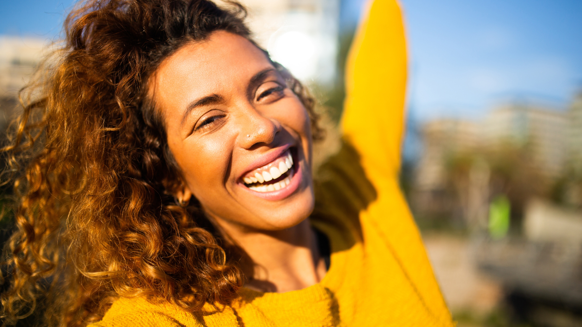 Selfie portrait of laughing young latin woman outside in the city.