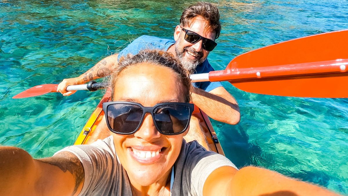Happy active adult couple enjoying kayak canoe excursion trip tour on transparent blue clean water at the sea. Concept of happiness man and woman in summer holiday vacation. Healthy lifestyle. Tourist.