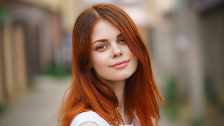 cute smiling girl looking at you with hair flying in the sunset.