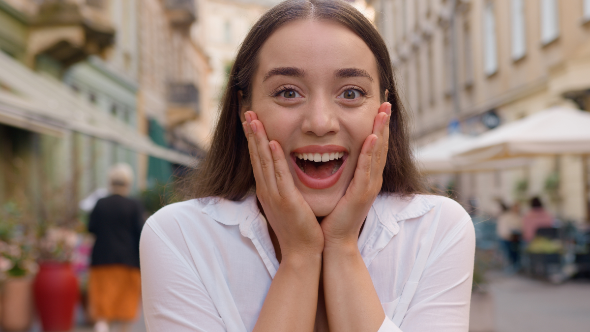 Close up portrait European surprised woman open mouth shocked caucasian girl city outside gen z female smiling success achievement win victory wonder cheerful joyful lady amazement expression street.