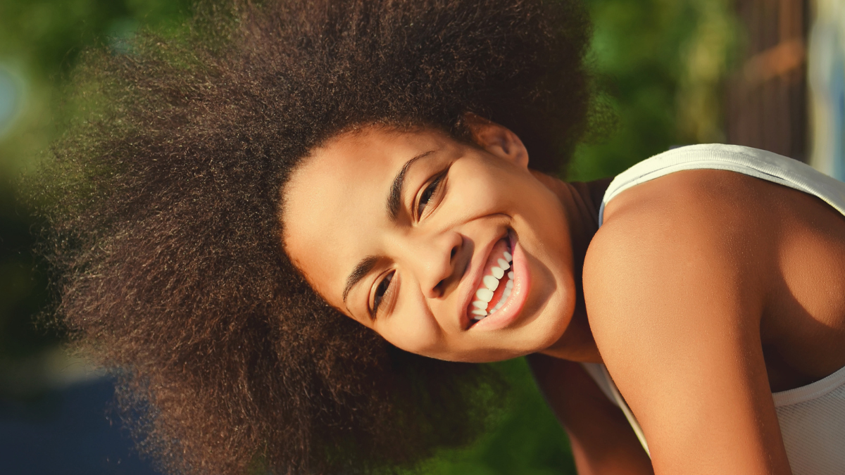 young happy and pretty afro wooman closeup portrait on natural background.