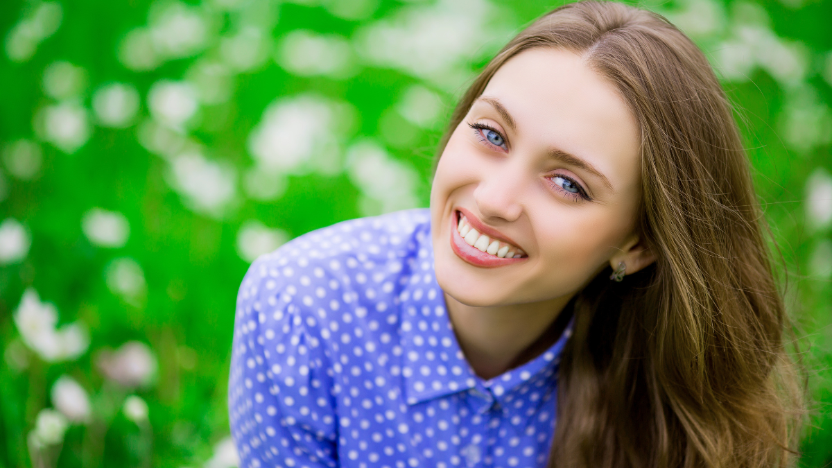 beautiful young woman outdoors, on the meadow with white flowers.