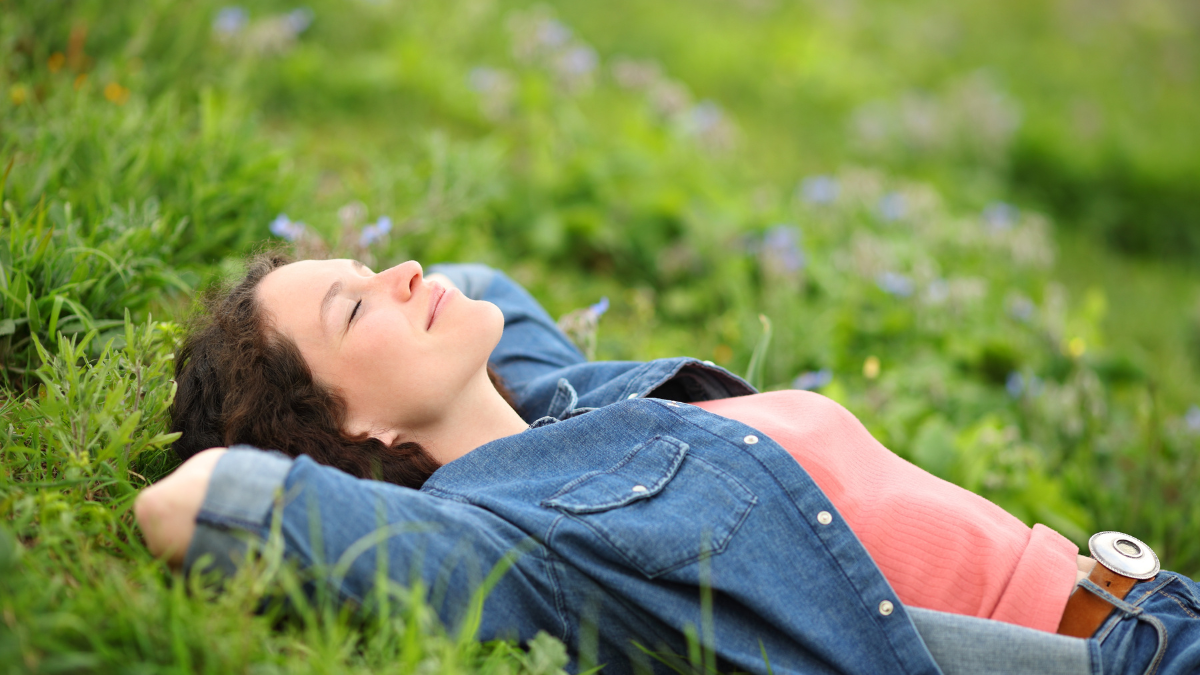 Beautiful woman resting and relaxing lying on the grass in a park.