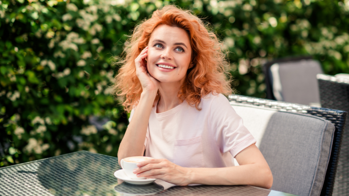 Photo of lovely dreamy cute woman sitting in cafe drinking tasty cappuccino cafe summer terrace outside.