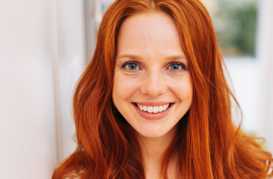 Young and pretty red-haired woman close-up front portrait, with beautiful smile, shot indoors.