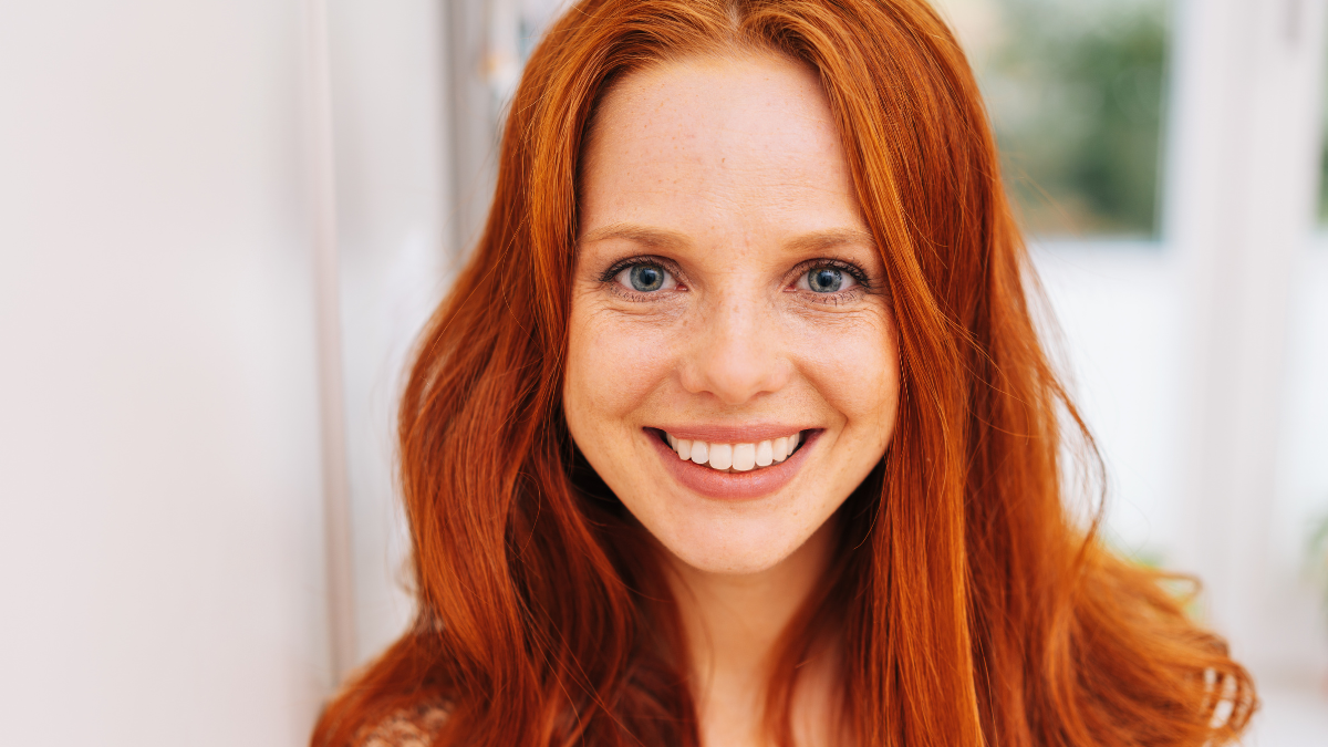 Young and pretty red-haired woman close-up front portrait, with beautiful smile, shot indoors.
