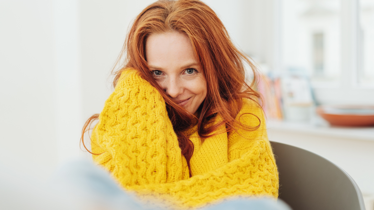 Cute young woman flirting with the camera smiling mischievously from an armchair.