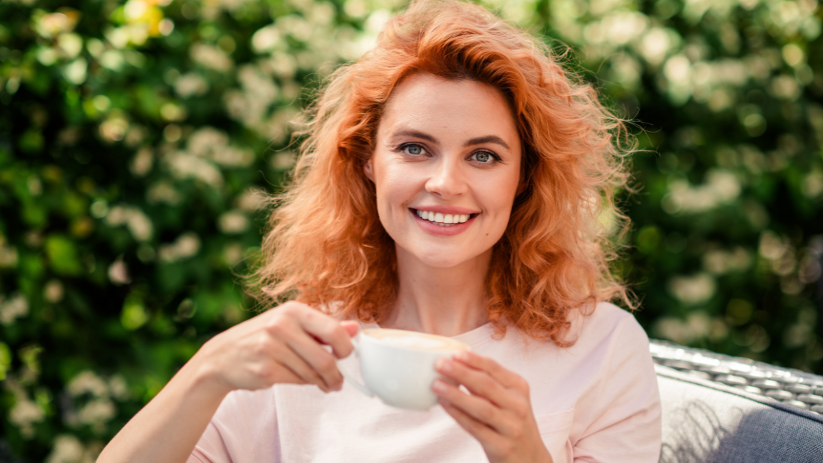 Photo of charming adorable cute woman enjoying weekend sitting in cafe summer terrace drinking latte.