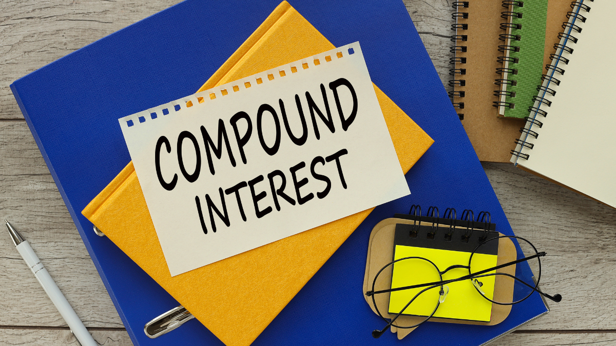 compound interest text on the page. yellow notepad on blue folder.