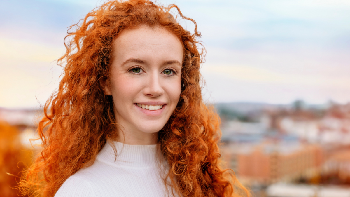 Closeup portrait of a young happy woman with red curly hair looking into the camera.