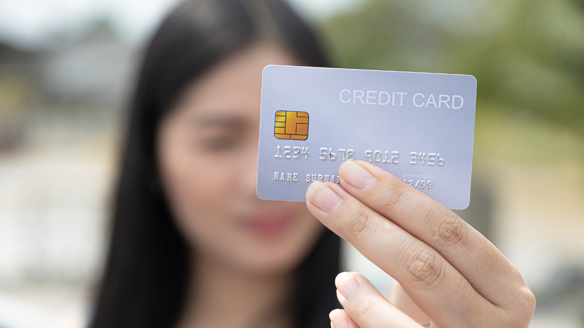 Closeup hand takes of credit card for financial transactions and blurred background women.
