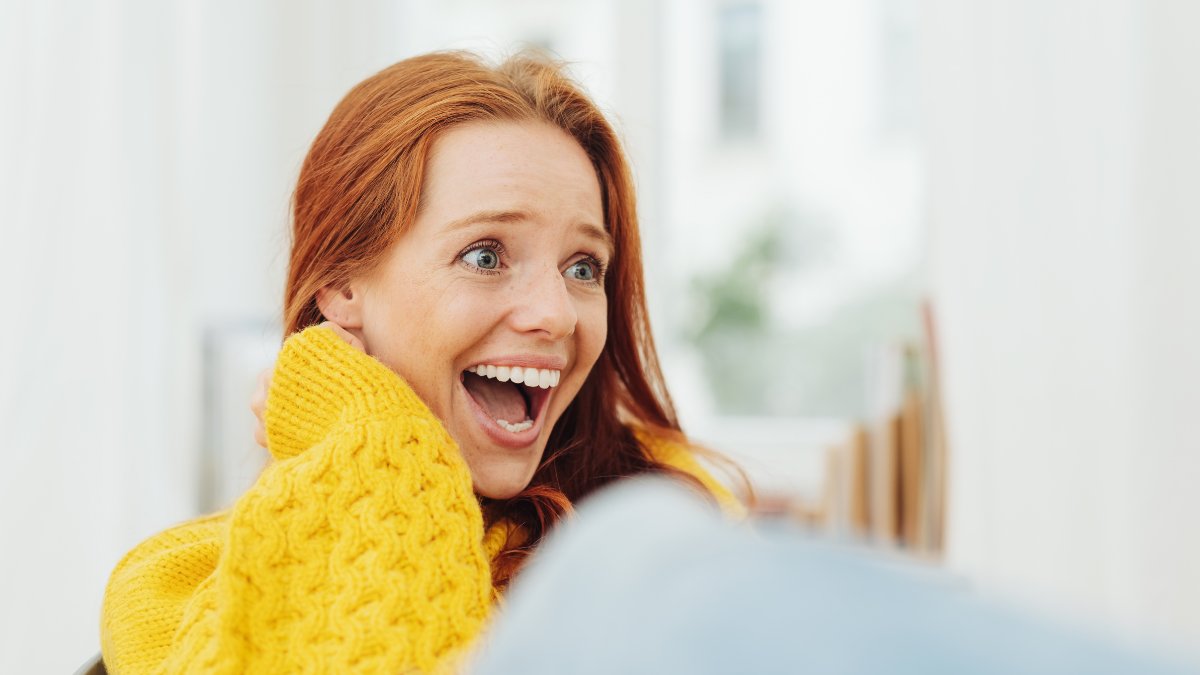 Amused young woman enjoying a good laugh indoors at home in a close up portrait.