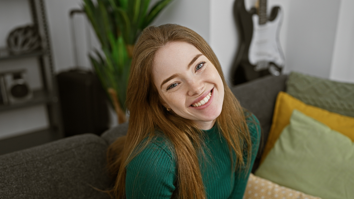 Portrait of a cheerful young woman relaxing on a couch in a cozy living room with modern decor.