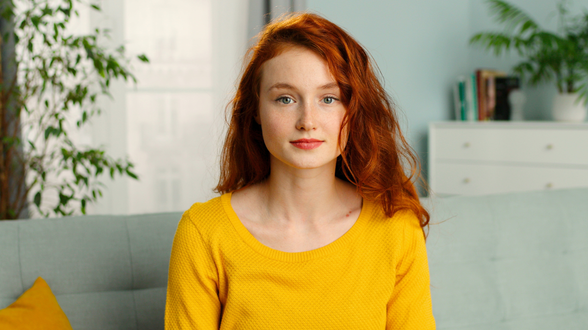 Portrait of joyful redhead girl looking with serious face at camera.
