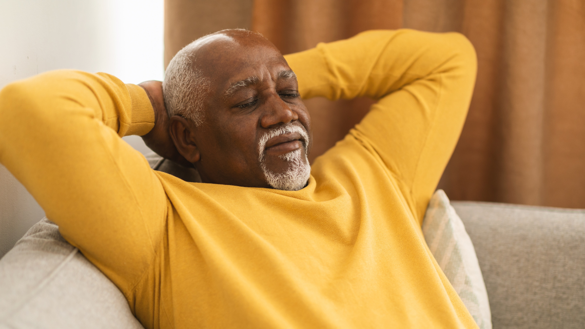Senior Black Man Sleeping Holding Hands Behind Head Sitting On Sofa At Home. Mature Male Relaxing Resting With Eyes Closed, Napping On Couch. Rest And Relaxation Concept. Panorama.