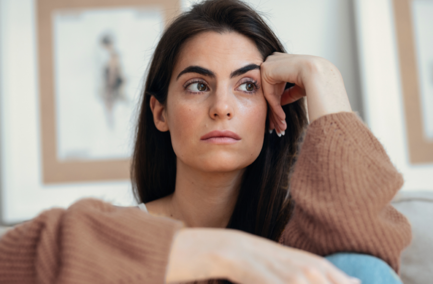 Shot of depressed young woman overthinking while sitting on the couch at home.