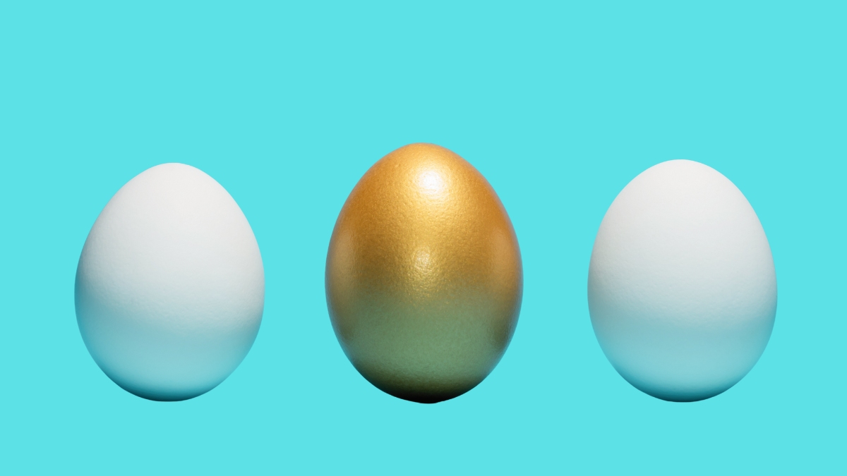 Golden egg between two white eggs on a blue background. Concept of exclusivity, individuality, best choice.