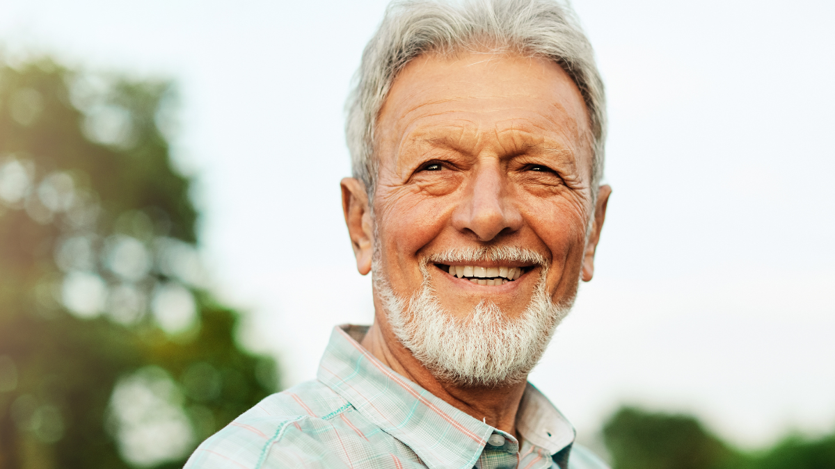 Portrait of an elderly man outdoors. Happy senior man in park.