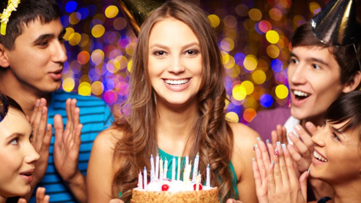 Portrait of joyful girl holding birthday cake surrounded by friends at party free birthday food.