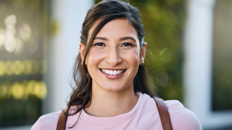 Woman, travel and portrait of a young person from Japan with a smile and blurred background. Backpack, happiness and freedom of a female in summer on a urban adventure for traveling on vacation.